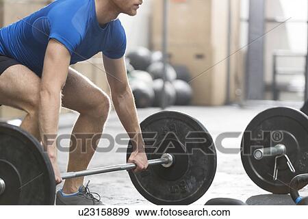 Low section of dedicated man lifting barbell in crossfit gym View Large Photo Image Stock Photo - Low section of dedicated man lifting barbell in crossfit gym. Fotosearch