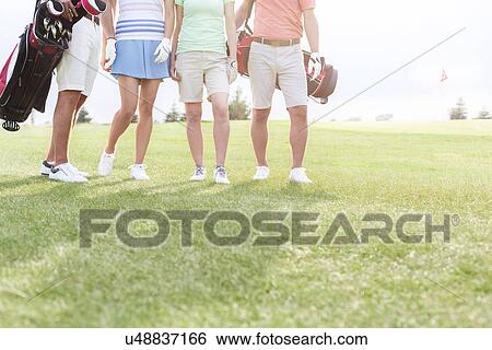 Stock Photograph - Low section of friends standing at golf course. Fotosearch