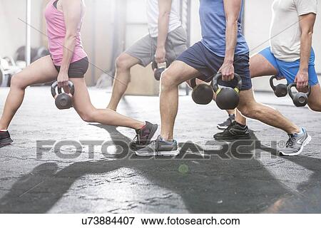 Stock Photo - Low section of people lifting kettlebells at crossfit gym. Fotosearch