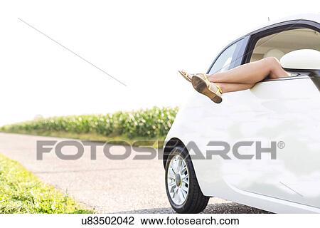 Low section of woman relaxing in car on country road View Large Photo Image Stock Image - Low section of woman relaxing in car on country road. Fotosearch