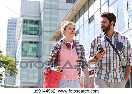 Male and female friends walking outside office building on sunny day View Large Photo Image Stock Image - Male and female friends walking outside office building on sunny day. Fotosearch