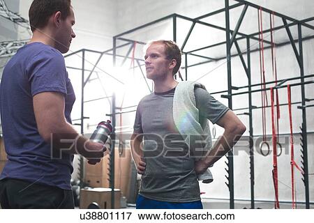 Stock Photo - Male friends talking in crossfit gym. Fotosearch
