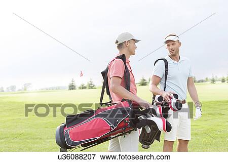 Male golfers communicating at golf course against clear sky View Large Photo Image Stock Photo - Male golfers communicating at golf course against clear sky. Fotosearch