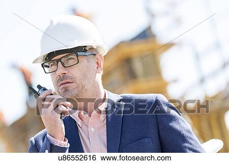 Male supervisor using walkie-talkie at construction site View Large Photo Image Stock Photograph - Male supervisor using walkie-talkie at construction site. Fotosearch
