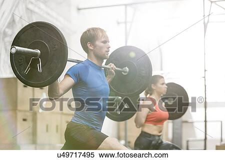 Man and woman lifting barbells in crossfit gym View Large Photo Image Stock Photography - Man and woman lifting barbells in crossfit gym. Fotosearch