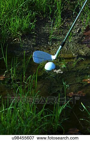 Stock Photo - Man chipping ball from water hazard. Fotosearch