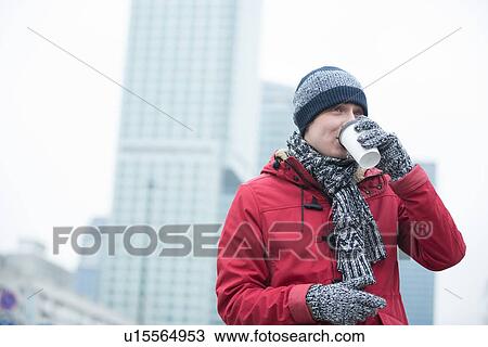 Stock Image - Man in warm clothing drinking coffee outdoors. Fotosearch