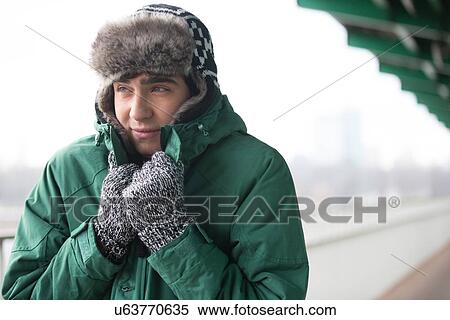 Stock Photography - Man in warm clothing shivering outdoors. Fotosearch