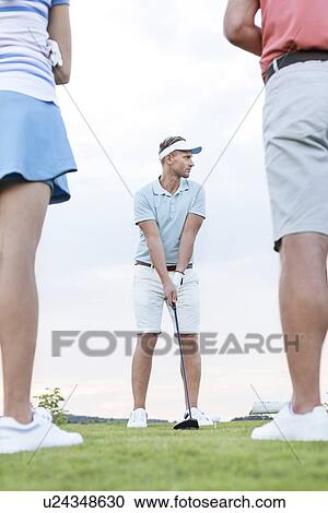 Man playing golf against sky with friends standing in foreground View Large Photo Image Stock Image - Man playing golf against sky with friends standing in foreground. Fotosearch