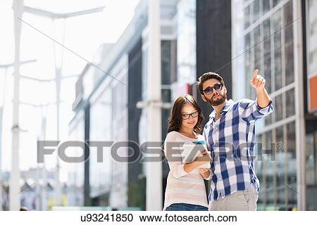 Man pointing while woman using digital tablet outside building View Large Photo Image Stock Image - Man pointing while woman using digital tablet outside building. Fotosearch