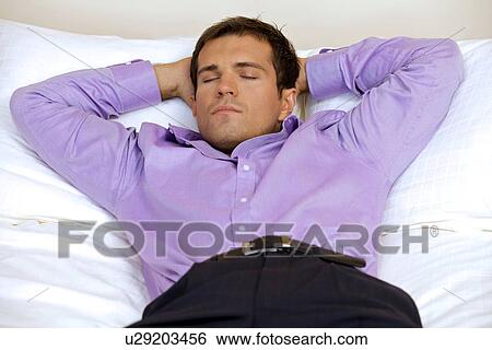 Man relaxing in hotel room with hands behind head, eyes closed View Large Photo Image Stock Photograph - Man relaxing in hotel room with hands behind head, eyes closed. Fotosearch