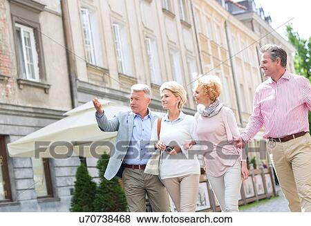 Man showing something to friends while walking in city View Large Photo Image Stock Photo - Man showing something to friends while walking in city. Fotosearch