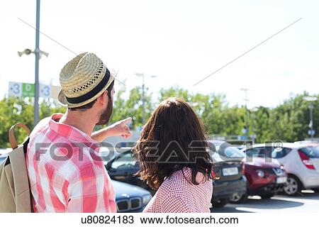 Stock Image - Man showing something to woman on city street against clear sky. Fotosearch