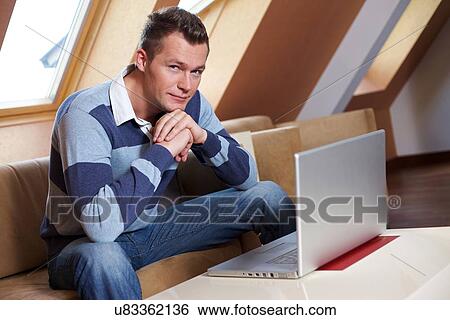 Man sitting on sofa View Large Photo Image Stock Photograph - Man sitting on sofa. Fotosearch