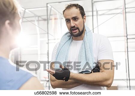 Stock Photo - Man talking to male friend in crossfit gym. Fotosearch