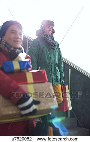 Stock Image - Men with gift boxes and shopping bags standing on steps. Fotosearch