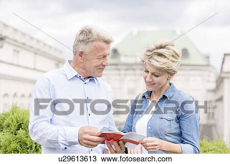 Middle-aged couple reading guidebook outside building View Large Photo Image Stock Image - Middle-aged couple reading guidebook outside building. Fotosearch