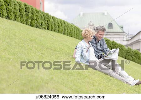 Middle-aged couple reading map while sitting at park View Large Photo Image Stock Photograph - Middle-aged couple reading map while sitting at park. Fotosearch