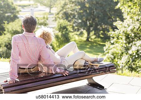 Middle-aged couple relaxing on park bench View Large Photo Image Stock Image - Middle-aged couple relaxing on park bench. Fotosearch