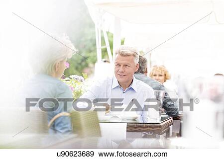 Middle-aged couple sitting at sidewalk cafe on sunny day View Large Photo Image Stock Photo - Middle-aged couple sitting at sidewalk cafe on sunny day. Fotosearch