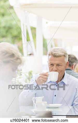 Middle-aged man looking at woman while having coffee at sidewalk cafe View Large Photo Image Stock Image - Middle-aged man looking at woman while having coffee at sidewalk cafe. Fotosearch
