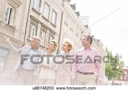 Middle-aged man showing something to friends while walking in city View Large Photo Image Stock Image - Middle-aged man showing something to friends while walking in city. Fotosearch