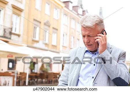 Middle-aged man using mobile phone in city View Large Photo Image Picture - Middle-aged man using mobile phone in city. Fotosearch