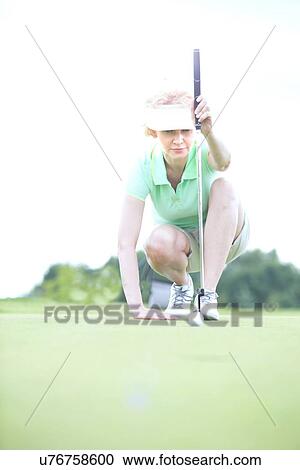 Middle-aged woman aiming ball at golf course View Large Photo Image Stock Image - Middle-aged woman aiming ball at golf course. Fotosearch