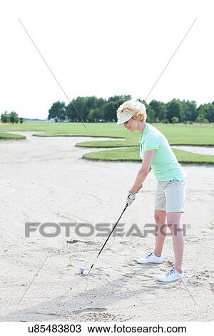 Middle-aged woman playing golf at course against clear sky View Large Photo Image Stock Image - Middle-aged woman playing golf at course against clear sky. Fotosearch