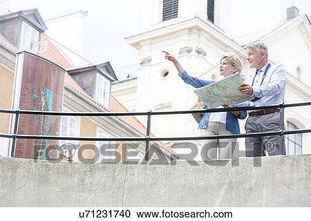 Middle-aged woman showing something to man while reading map by railing View Large Photo Image Stock Image - Middle-aged woman showing something to man while reading map by railing. Fotosearch