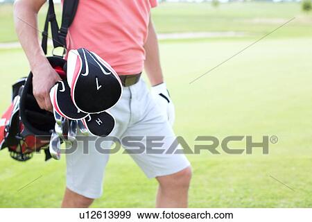 Midsection of man carrying golf club bag at course View Large Photo Image Stock Photo - Midsection of man carrying golf club bag at course. Fotosearch