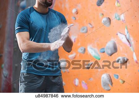 Stock Photograph - Midsection of man dusting powder by climbing wall in crossfit gym. Fotosearch