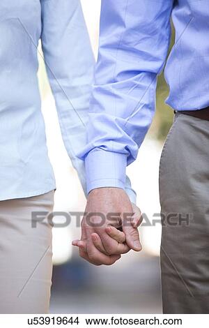 Midsection of middle-aged couple holding hands outdoors View Large Photo Image Picture - Midsection of middle-aged couple holding hands outdoors. Fotosearch
