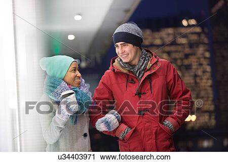 Stock Image - Multiethnic couple conversing at dusk during winter. Fotosearch