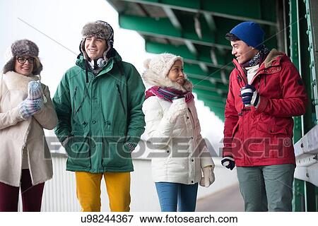 Multiethnic friends in winter wear conversing outdoors View Large Photo Image Stock Photo - Multiethnic friends in winter wear conversing outdoors. Fotosearch