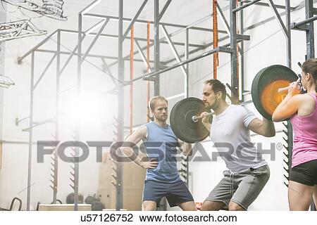 People assisting man in lifting barbell at crossfit gym View Large Photo Image Stock Image - People assisting man in lifting barbell at crossfit gym. Fotosearch