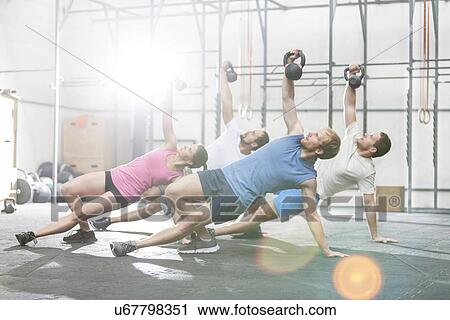 Stock Image - People exercising with kettlebells at crossfit gym. Fotosearch