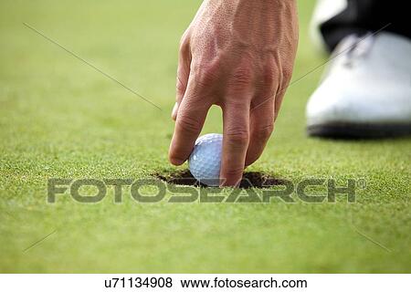 Stock Photo - Person holding golf ball, close-up. Fotosearch