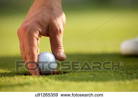 Stock Photo - Person holding golf ball, close-up. Fotosearch