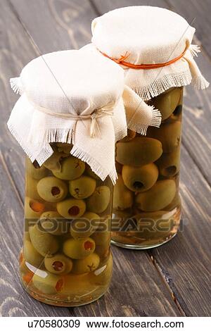 Stock Photo - Pickled olives in jar on wooden table. Fotosearch