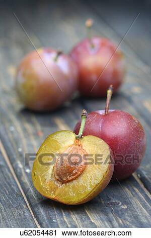 Stock Image - Plums on wooden table - close-up. Fotosearch
