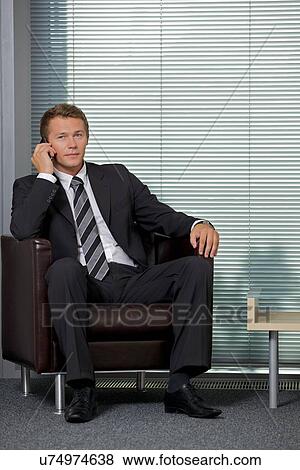 Stock Photo - Portrait of businessman using mobile phone in office. Fotosearch