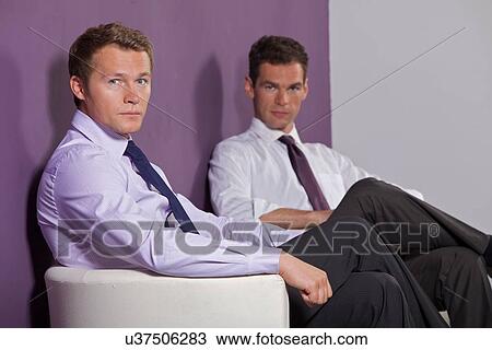 Stock Image - Portrait of businessmen sitting at office. Fotosearch