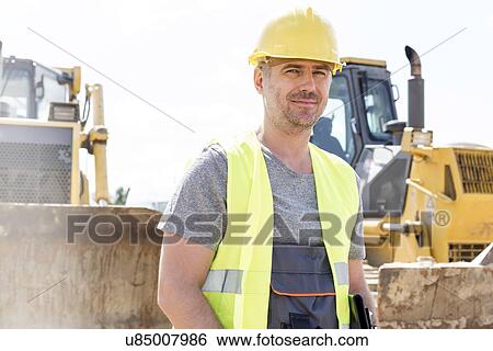 Stock Photograph - Portrait of confident supervisor standing at construction site. Fotosearch