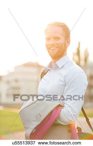 Stock Photo - Portrait of happy businessman standing outdoors on sunny day. Fotosearch