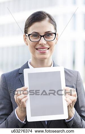 Portrait of happy businesswoman showing digital tablet outdoors View Large Photo Image Picture - Portrait of happy businesswoman showing digital tablet outdoors. Fotosearch