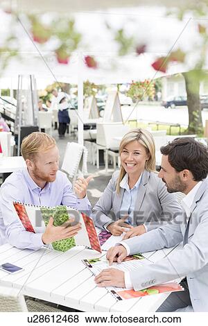 Portrait of happy businesswoman with male colleagues deciding menu at sidewalk cafe View Large Photo Image Stock Photo - Portrait of happy businesswoman with male colleagues deciding menu at sidewalk cafe. Fotosearch