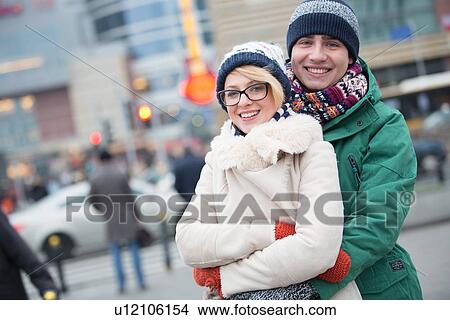 Portrait of happy couple embracing on city street during winter View Large Photo Image Picture - Portrait of happy couple embracing on city street during winter. Fotosearch