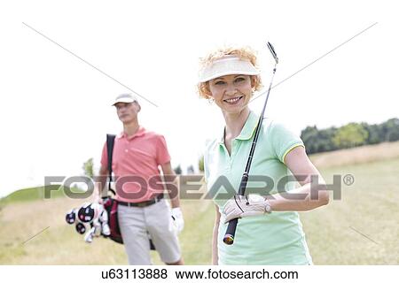 Portrait of happy female golfer with friend standing in background View Large Photo Image Stock Photo - Portrait of happy female golfer with friend standing in background. Fotosearch