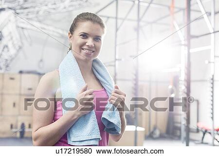 Portrait of happy woman holding towel around neck in crossfit gym View Large Photo Image Stock Image - Portrait of happy woman holding towel around neck in crossfit gym. Fotosearch